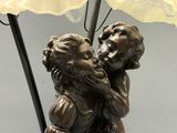 a bronze statue of a boy and a girl kissing under an umbrella