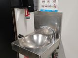 a stainless steel sink in a public restroom with a black door