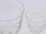 two clear wine glasses sitting next to each other on a white surface