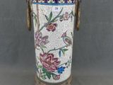 un vase orné d'un motif floral, posé sur un socle