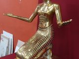une statue en or représentant une femme assise sur une table rouge