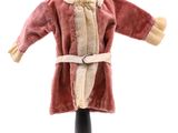 une poupée vêtue d'un manteau rouge et d'une écharpe blanche, posée sur un mannequin noir