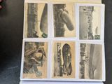 a lot of old photos on a table with a person holding a cell phone