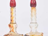 deux bougeoirs en verre avec des parties supérieures rouges sur fond blanc