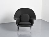 a black chair in a white room with a gray floor