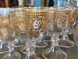 many glasses sitting on a table with a bottle in the background