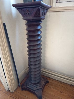 a tall wooden pedestal in the corner of a room