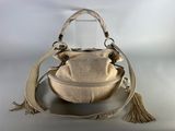 beige leather bucket bag with tassels and handles on display