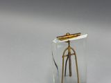 une bouteille en verre avec une poignée dorée, posée sur un socle