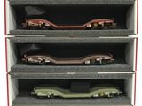 trois wagons de train miniature se trouvent dans une boîte posée sur une surface blanche