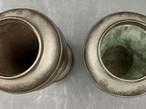 two silver vases sitting on a table next to each other