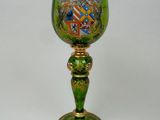 a green glass with a gold base and a coat of arms on it
