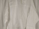 the white shirt is hanging on a hanger in front of a curtain