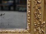 a mirror with a gold frame on a table