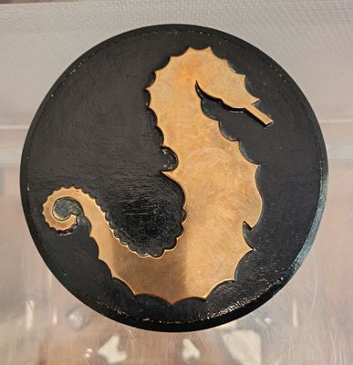 a black and gold seahorse on display in a glass case