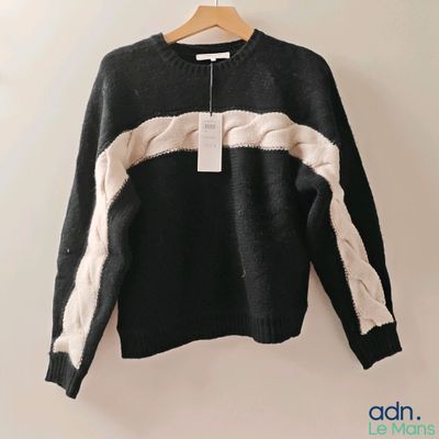 un pull noir et blanc suspendu à un cintre accroché au mur