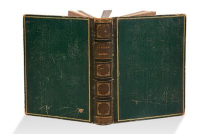 un livre vert ouvert sur une surface blanche