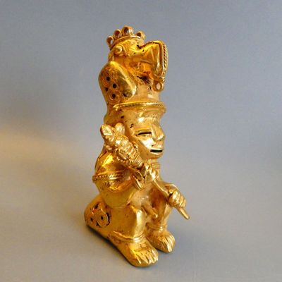 a gold figurine of a monkey sitting on a table