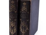 two old books sitting on top of each other on a white surface