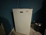 a small white refrigerator in the corner of a room