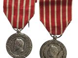 deux médailles ornées d'un ruban rouge et une médaille d'argent sur fond blanc