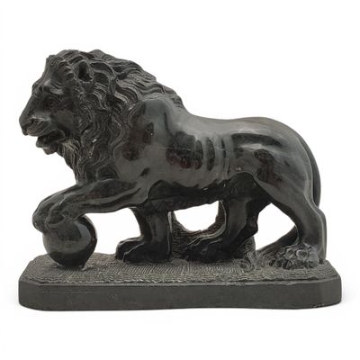 une statue représentant un lion tenant une balle dans la gueule