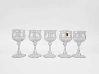 four wine glasses are lined up in a row on a white surface