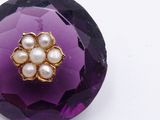 an image of a close up of a purple flower broochle with pearls