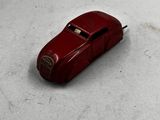 une petite voiture rouge posée sur une surface blanche