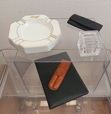 une table en verre sur laquelle se trouvent un étui à cigarettes et un cendrier en verre