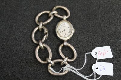 une montre attachée à une chaîne sur laquelle sont accrochés des pendentifs