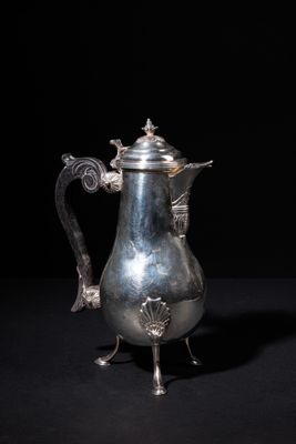 an antique silver coffee pot sitting on top of a black table
