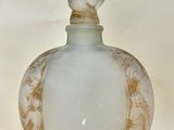 une petite bouteille en verre surmontée d'une figurine