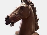 statue représentant une tête de cheval, posée sur un socle en bois, sur fond blanc