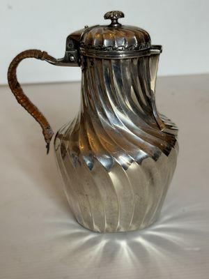 une cafetière en argent posée sur une table blanche