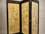 a black and gold screen with birds and flowers on it