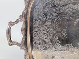 a silver tray with a handle and spoons next to it