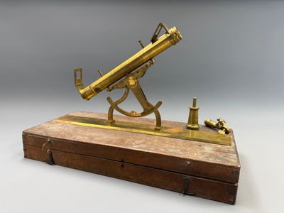 un télescope ancien en laiton posé sur un socle en bois, sur fond blanc