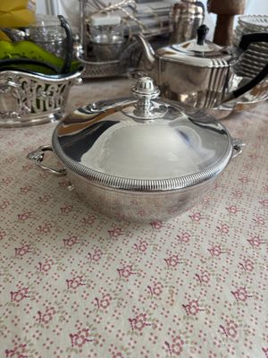 un bol en argent posé sur une table, à côté d'un bol de fruits