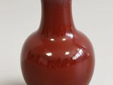 un vase rouge bordé de blanc posé sur une table