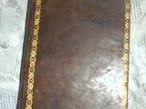 a brown leather book with gold trim on a table