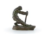 statue en bronze représentant un homme tenant un bâton, assis sur un rocher