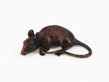 une petite figurine en bois représentant un rat, posée sur une surface blanche
