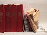 trois livres rouges empilés les uns sur les autres à côté d'un sac à dos