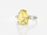 a yellow diamond and diamond ring on a white surface