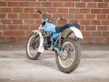 a blue and white dirt bike parked in front of a brick wall