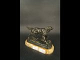 une statue en bronze représentant un chien, posée sur un socle en marbre