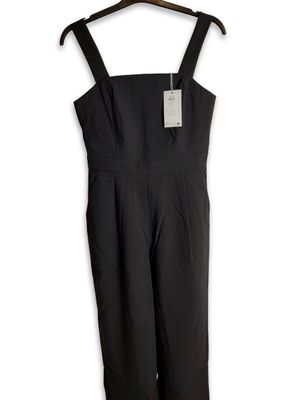 a black jumpsuit on a hanger on a white background