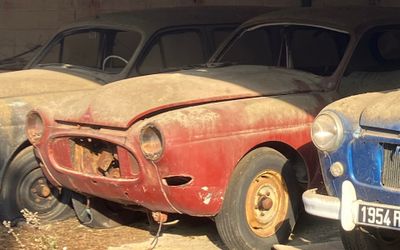 Plusieurs vieilles voitures sont garées en rangée dans un garage