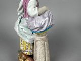 a figurine of a woman sitting on a stool reading a book